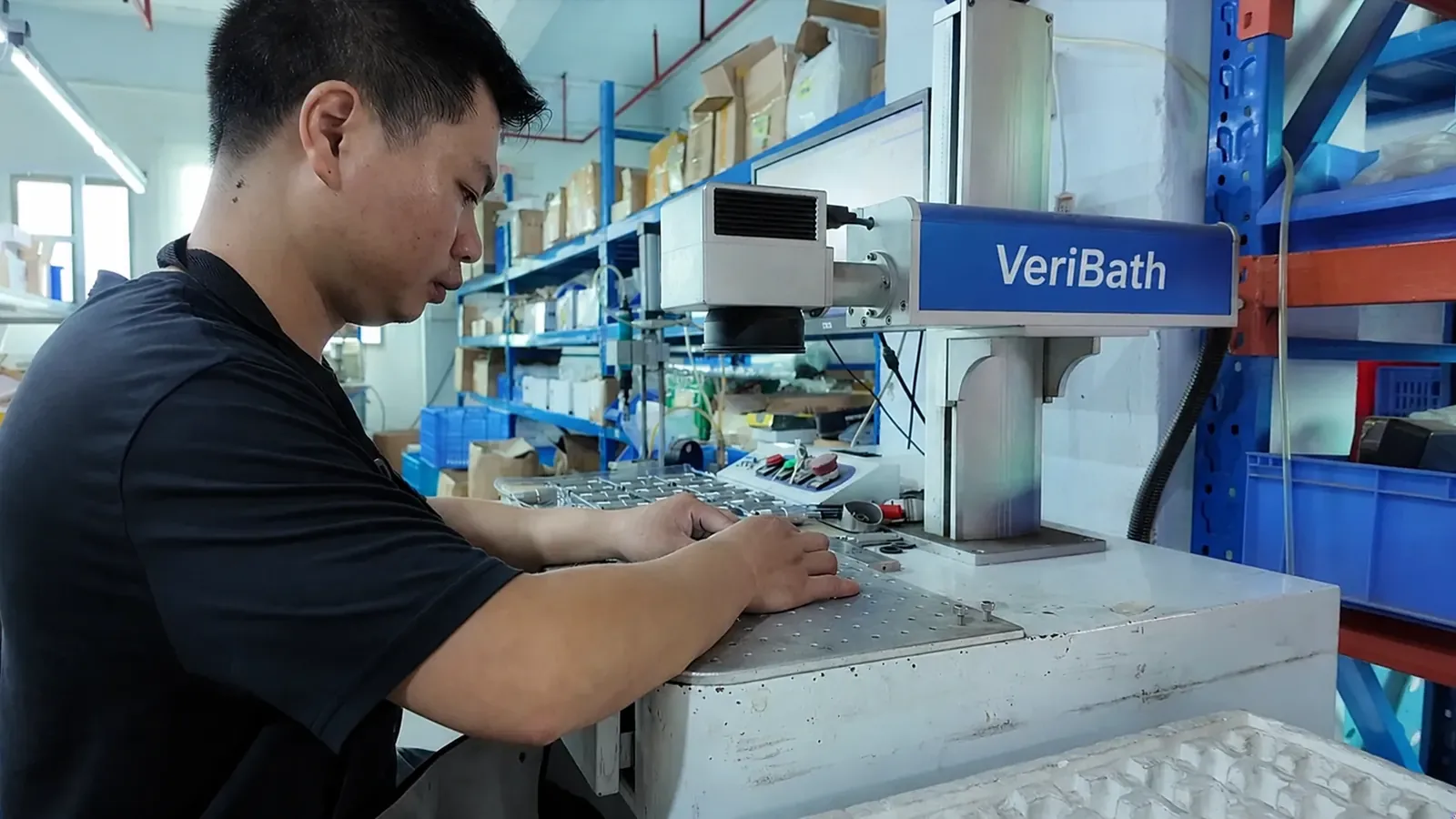 Operator at a VeriBath-branded laser marking station in the ZOOKV workshop